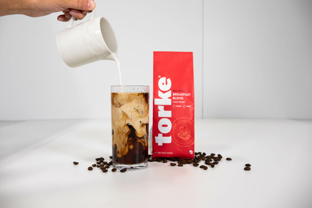 Cream being poured into a glass of Torke Coffee